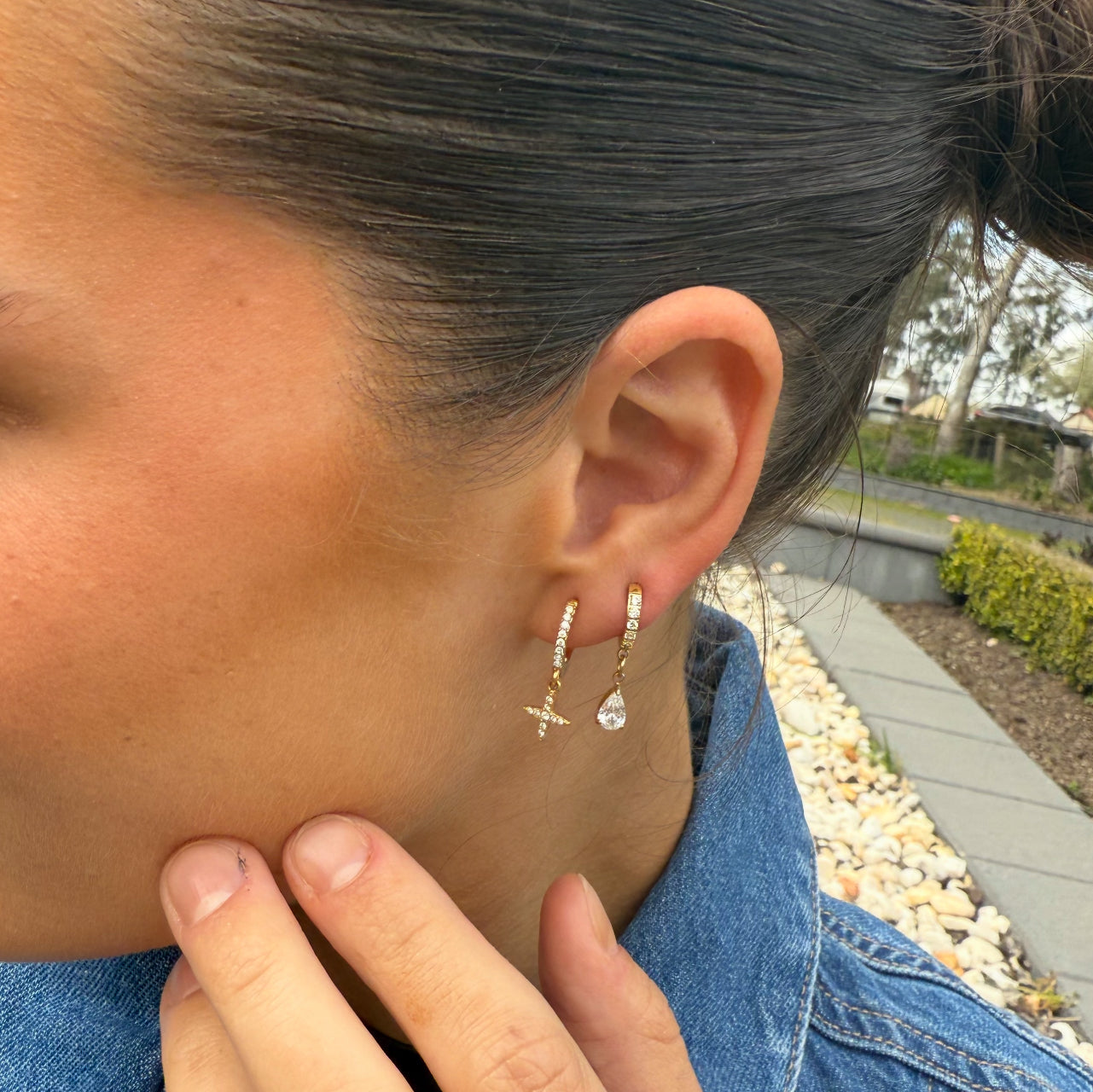 Close-up of a person wearing gold hoop earrings outdoors.