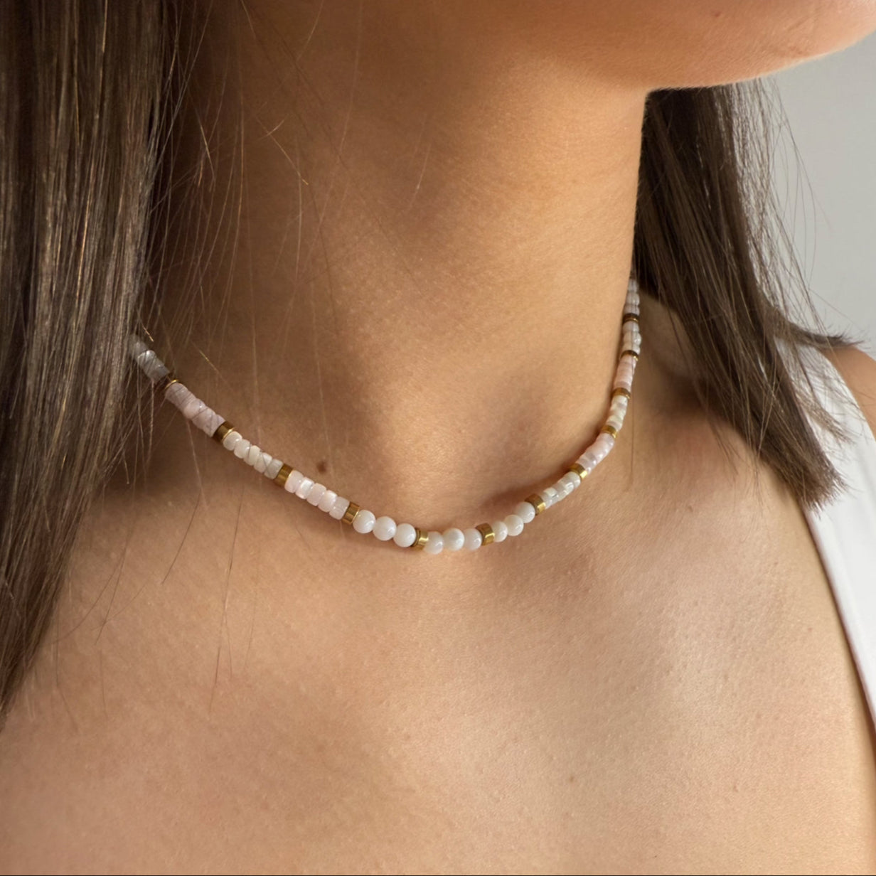 Pearl necklace worn by a person with a neutral background