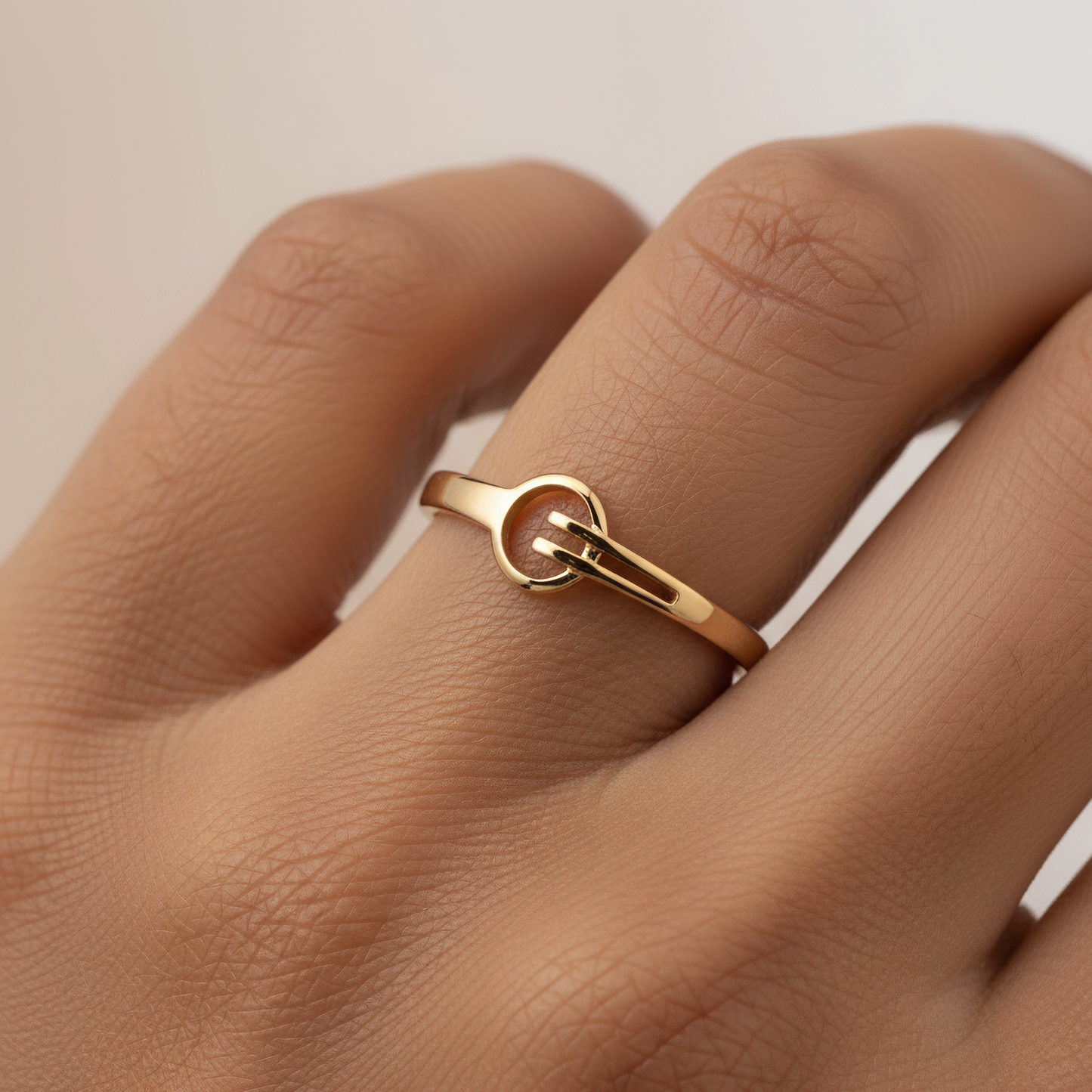 Gold ring on a person's finger against a neutral background