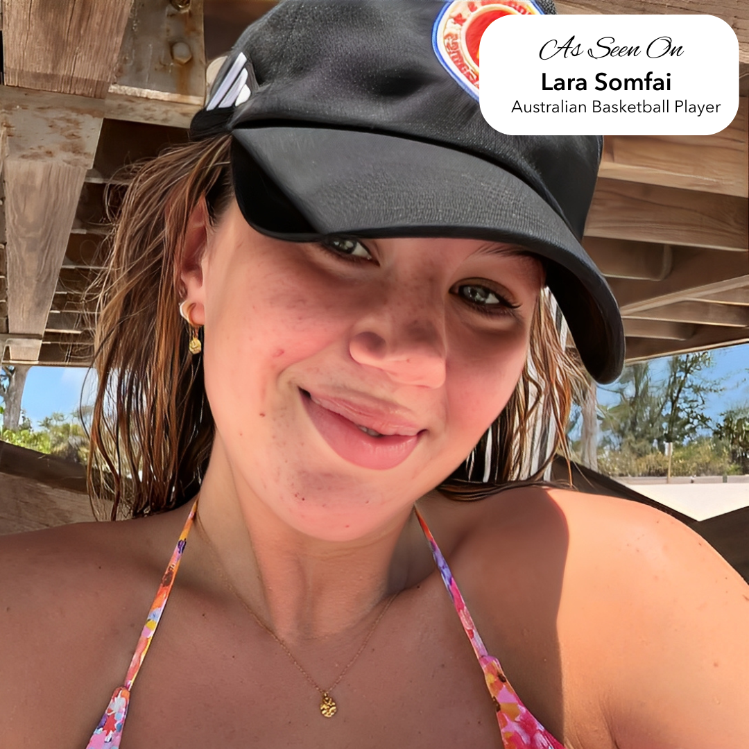 Woman wearing a black cap with a logo and text overlay, standing outdoors with Harmony Hoop Earrings
