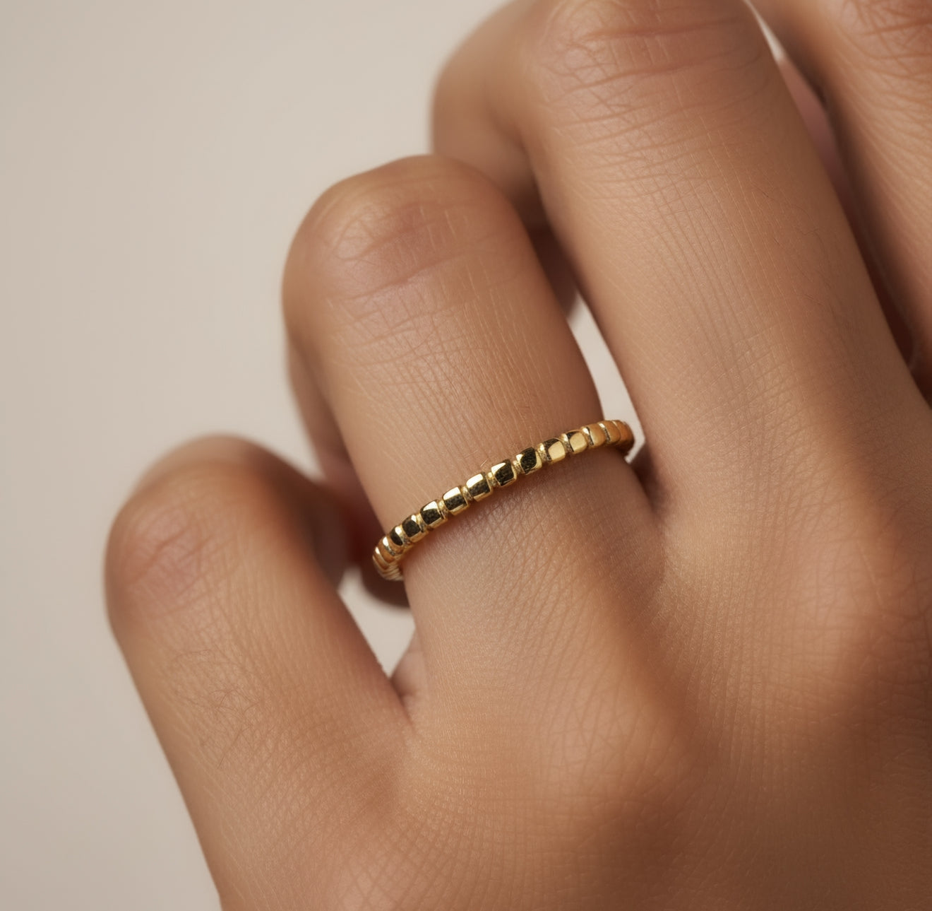 Gold ring on a person's finger against a neutral background