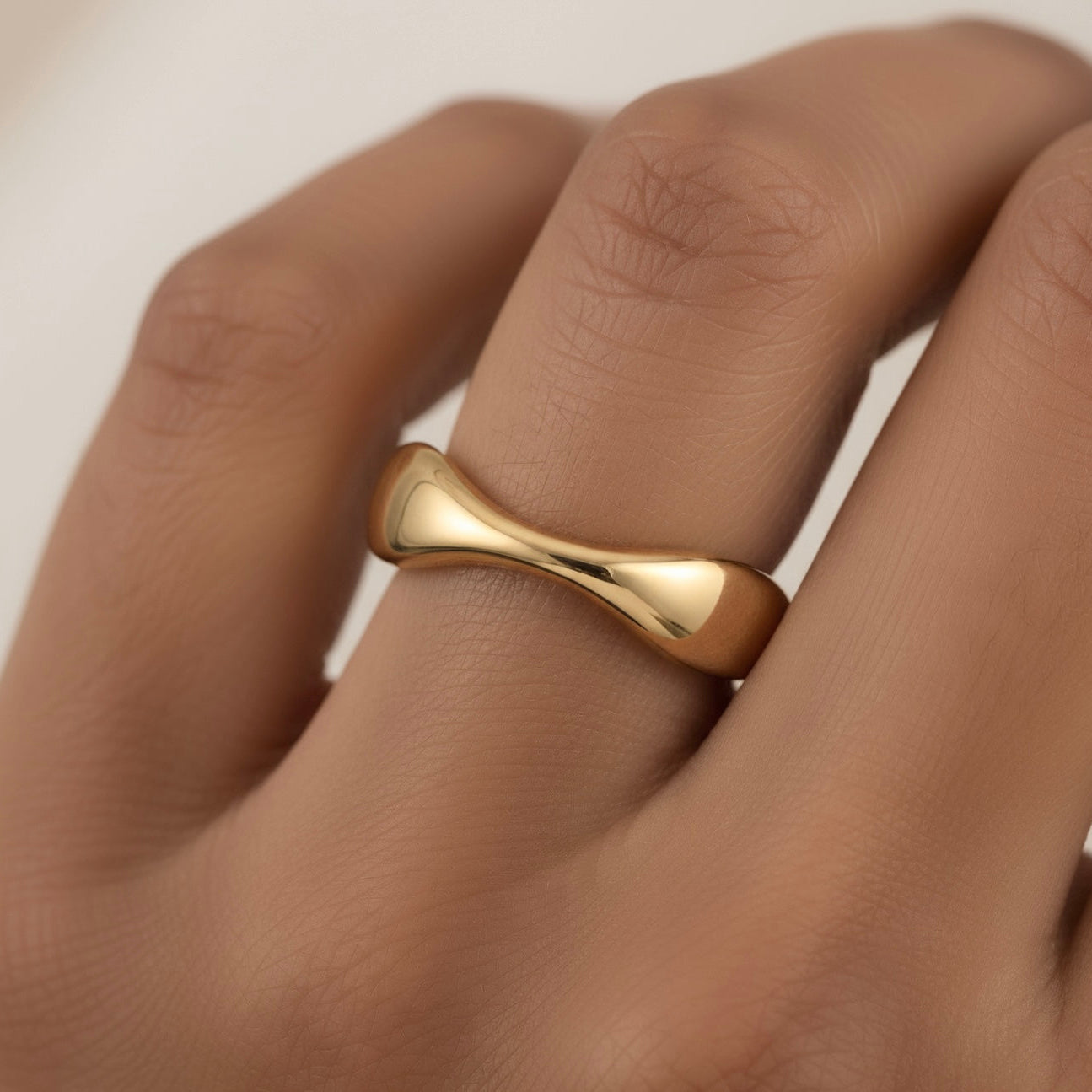 Gold ring on a finger with a plain background