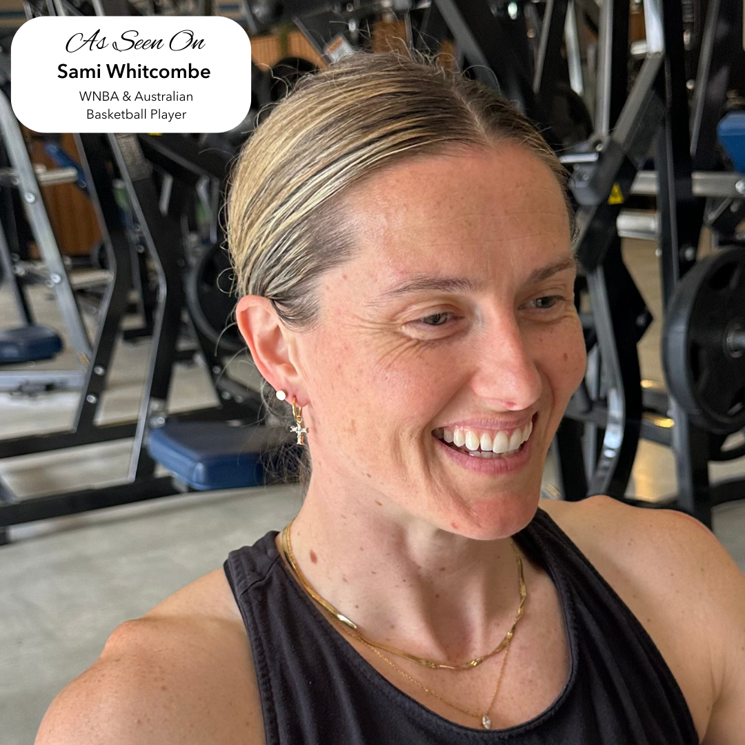 WNBA and Australian basketballer Sami Whitcomb smiling in a gym wearing EVER's gold jewellery, including layered necklaces and hoop earrings.