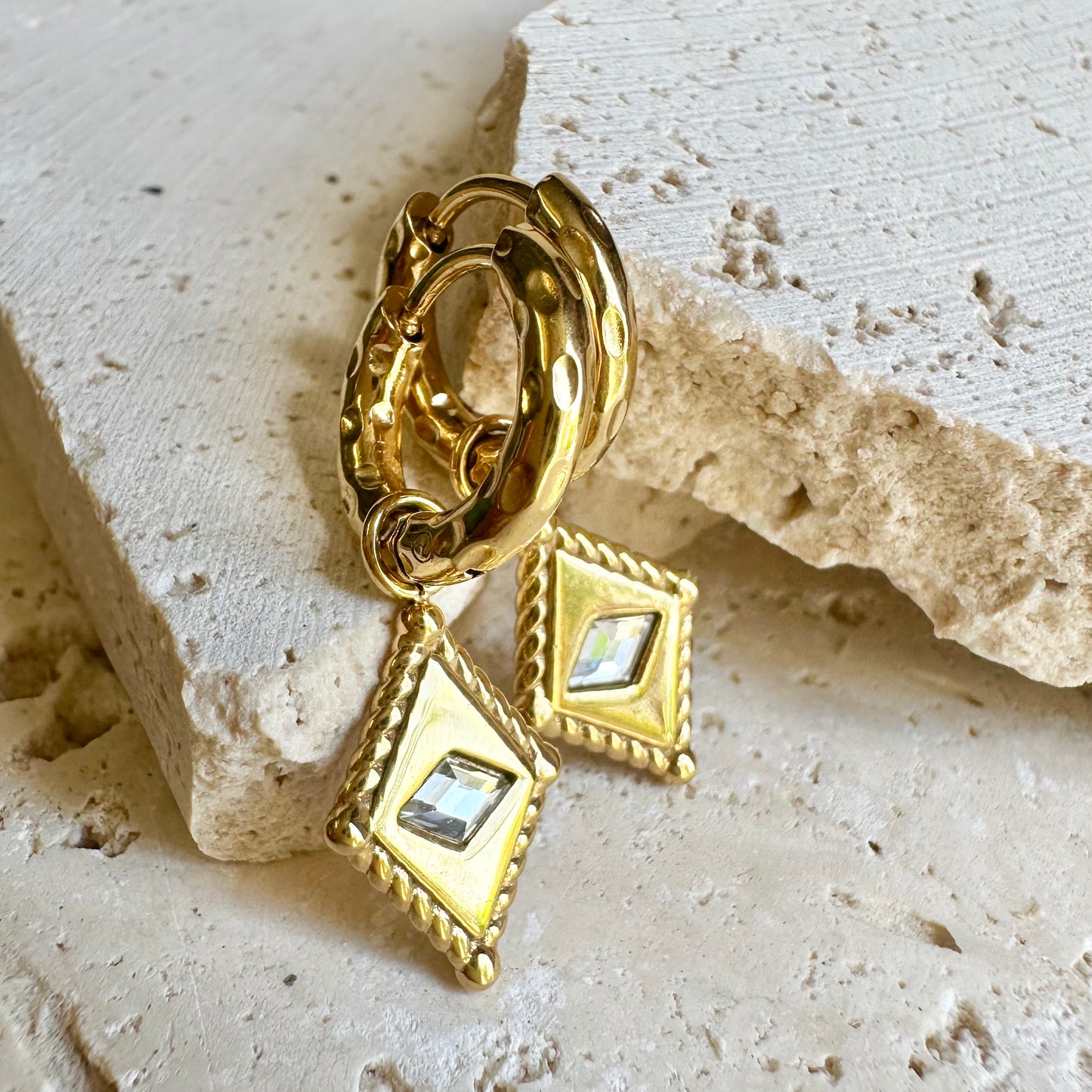 Arena Huggie Earrings – gold earrings with sculpted diamond charms styled on sandstone