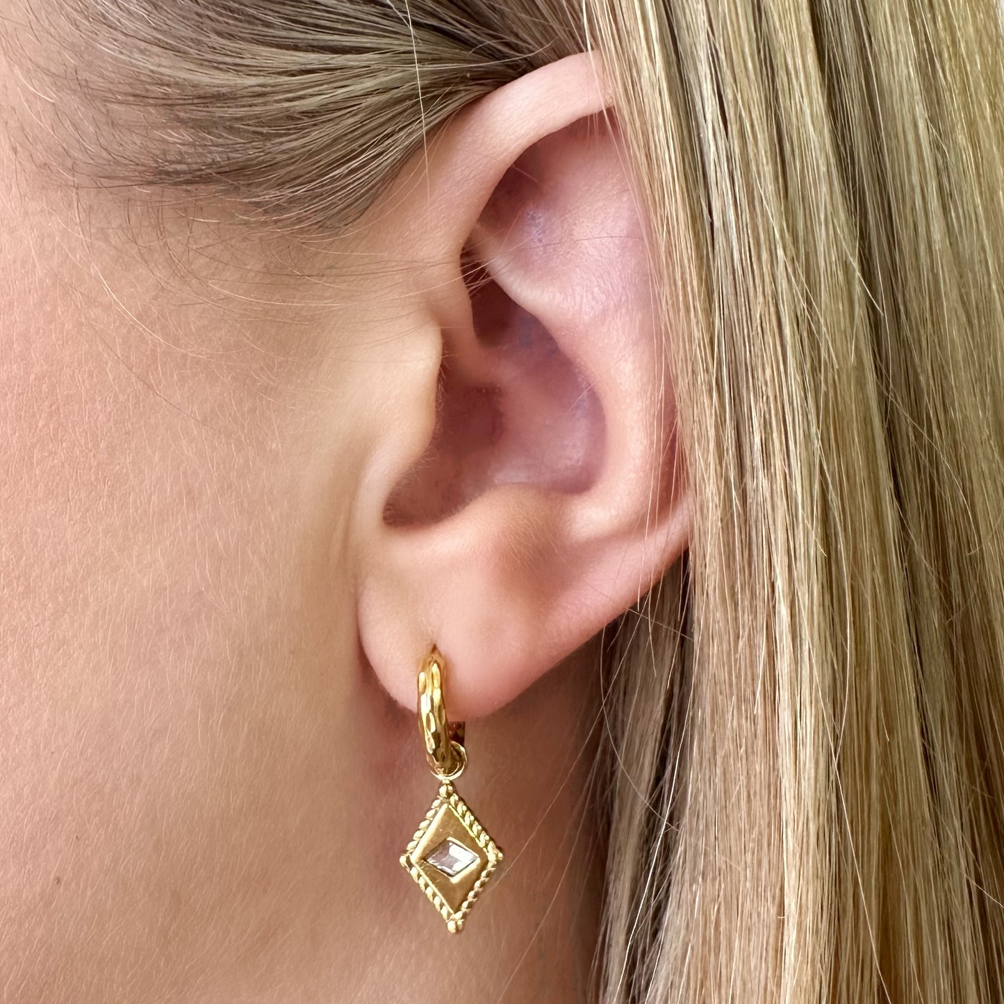 Arena Huggie Earrings worn – close-up of gold earrings with diamond charm on ear