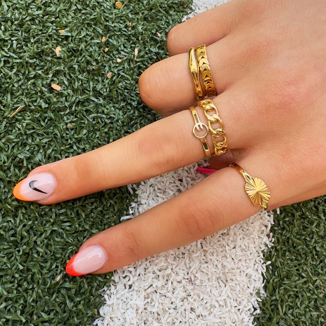EVER_activewear_jewellery_ gold_ring_finger_stack_flat_lay_image_model_shot_wearing_colourful_nail_polish_with_green_sports_grass_background_sweat_resistant_waterproof_anti-tarnish_durable