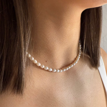 Pearl necklace worn by a person with a neutral background