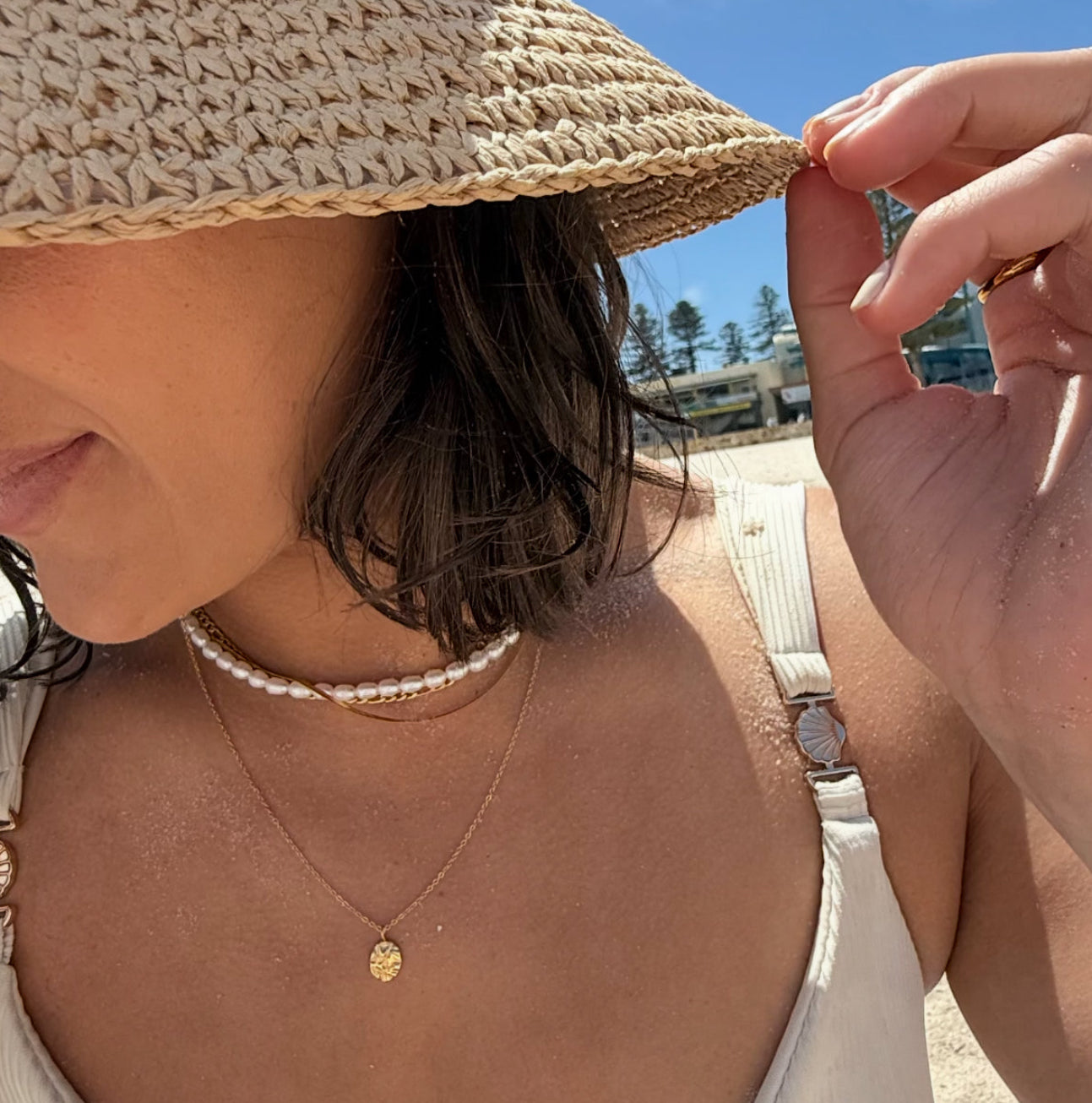 Woman adjusting a straw hat on a sunny day