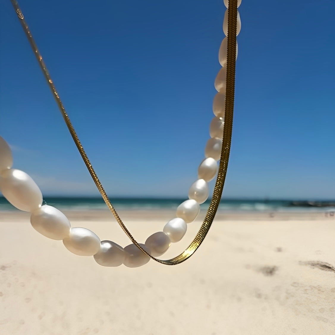 Pearl necklace on a sandy beach with a clear blue sky