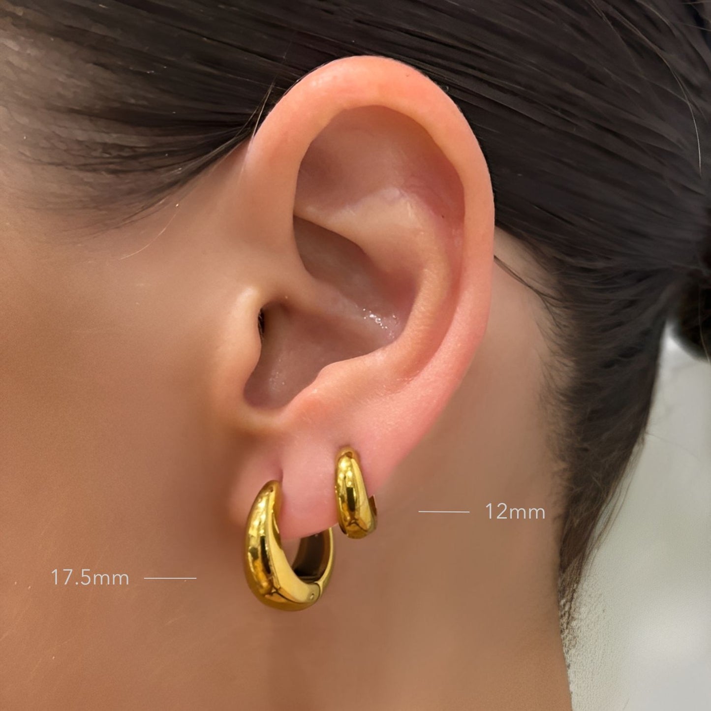 Gold hoop earrings worn, showing size measurements on an ear.