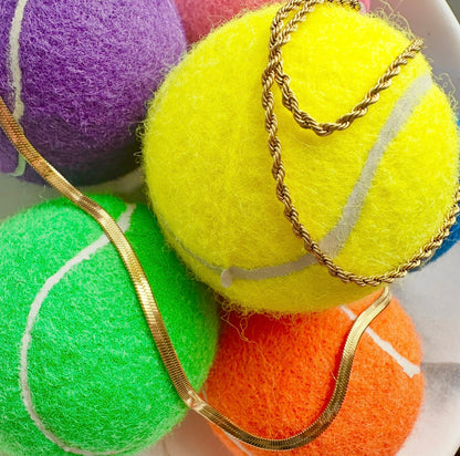 Colorful tennis balls with gold chains on a white surface