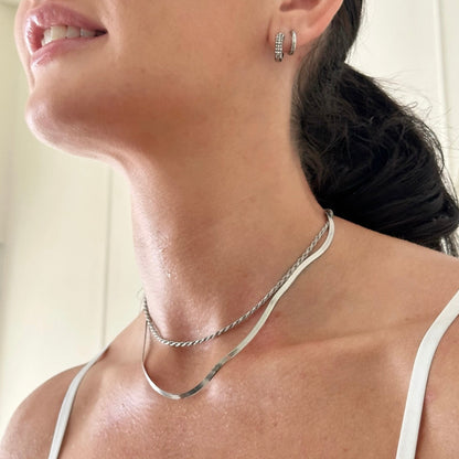 Close-up of a woman wearing a silver necklace and earrings.