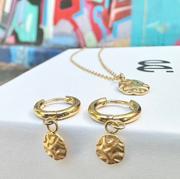 Harmony gold huggie earrings and necklace set displayed on white surface — EVER Jewellery