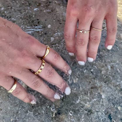 Two hands with gold rings on a textured surface