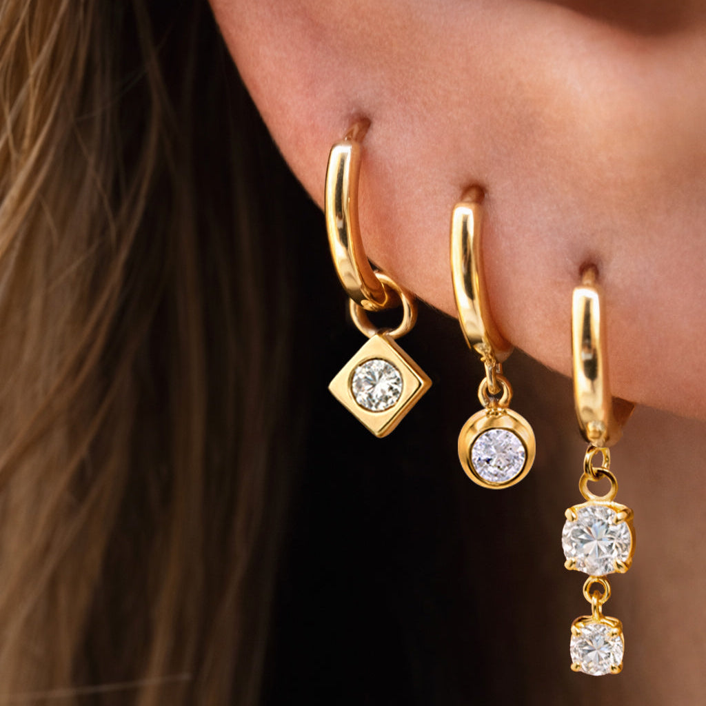 Gold hoop earrings with diamond accents worn by a person.