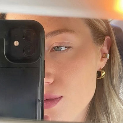 Close-up of a person holding a phone with a blurred background with the Podium Hoops on