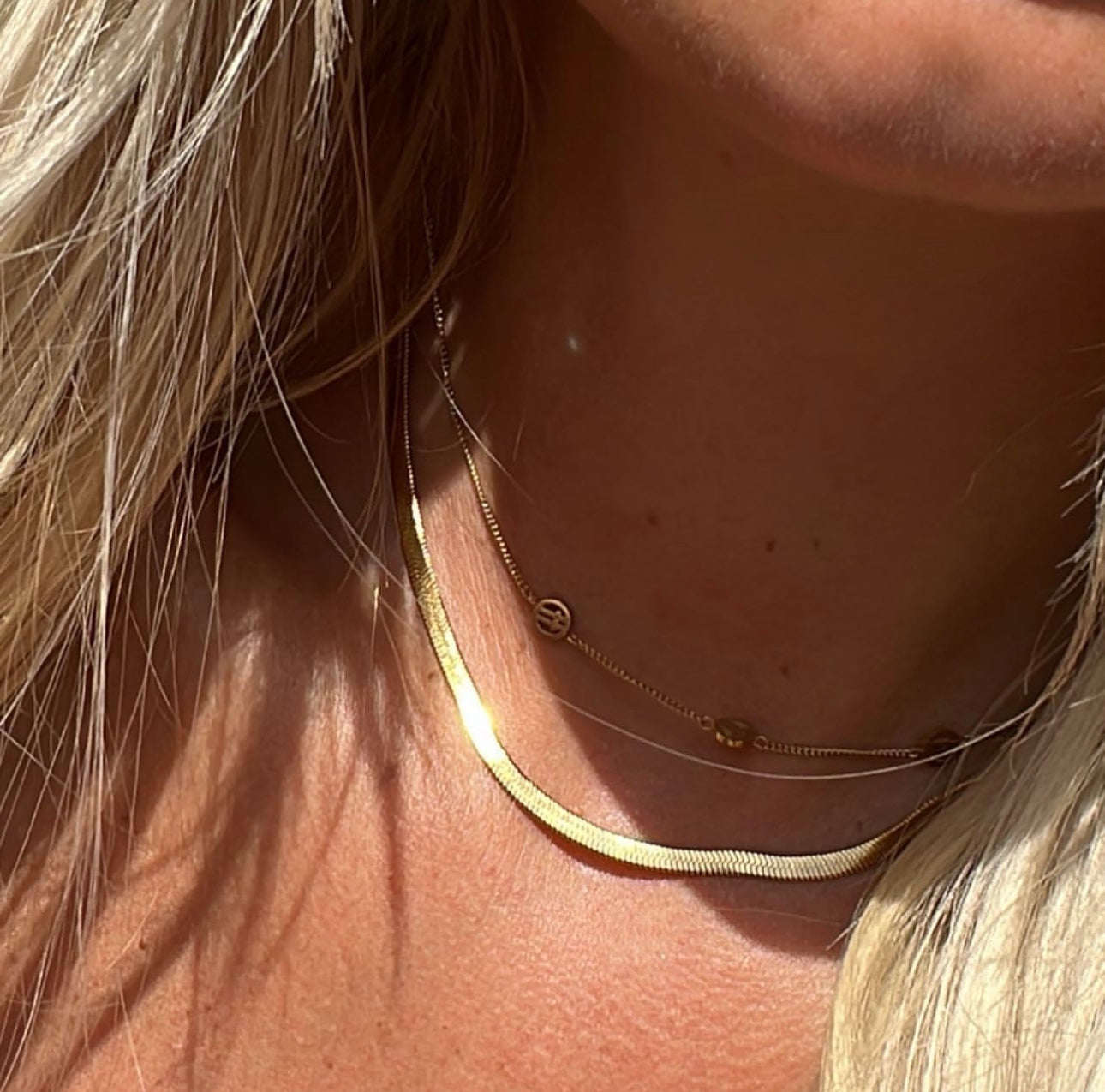 Close-up of a person wearing a gold necklace with a blurred background