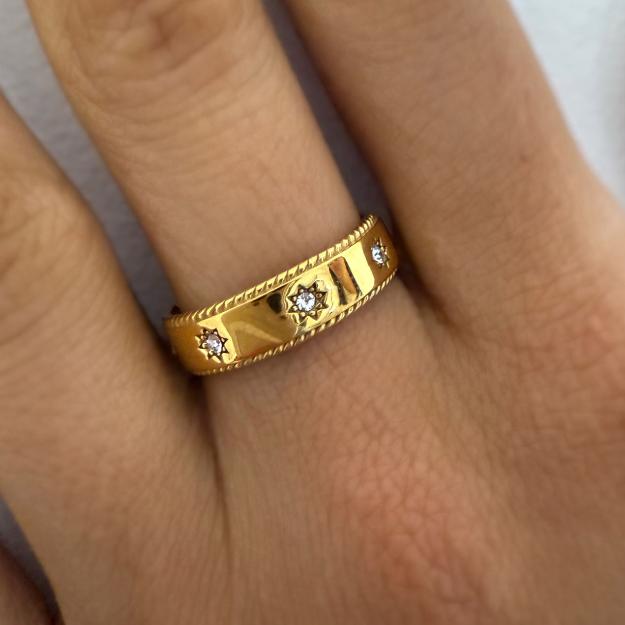 Gold ring with small diamonds on a finger