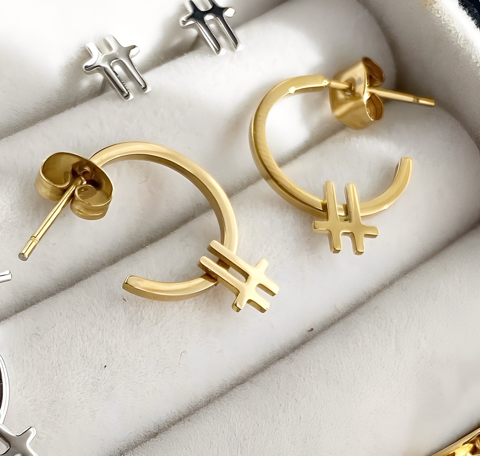 Gold earrings with unique designs on a white surface