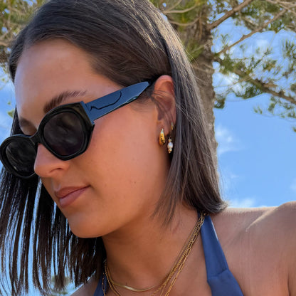 Woman wearing sunglasses with a blue sky and trees in the background